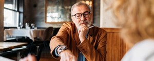 Professional man seated at table and talking to client