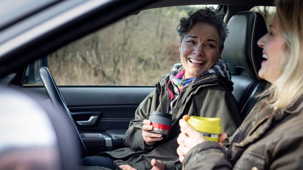 Women in car chatting and drinking coffee