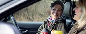 Women in car chatting and drinking coffee