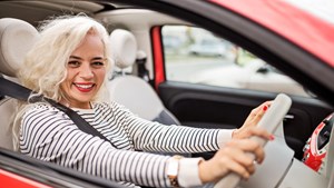 Smiling woman sitting in driver's seat in her car