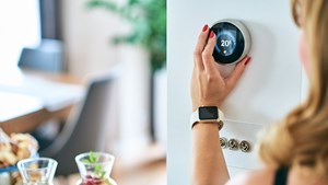 Woman turning the dial of a wall mounted digital thermostat