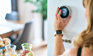 Woman turning the dial of a wall mounted digital thermostat