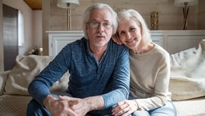 Relaxed looking older couple sitting on the end of their bed