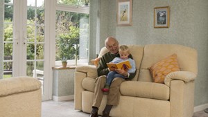 Grandfather and grandson sitting reading together on the sofa at home