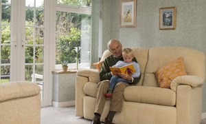 Grandfather and grandson sitting reading together on the sofa at home