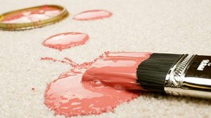 Brush covered in pink paint and spilled paint on pale carpet from renovation