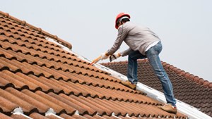 A man making repairs to the outside of a roof.