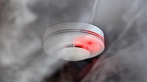 Close up of home fire alarm surrounded by smoke