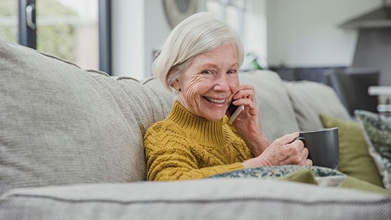 Older woman sitting talking on mobile phone with mug of tea