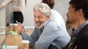 Man back to work and talking to young coworker