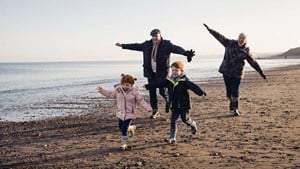 Grandparents and children running along beach