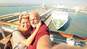 Couple on holiday taking a selfie overlooking a cruise ship