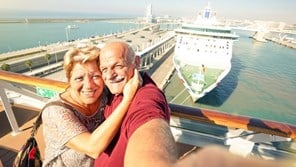 Couple on holiday taking a selfie overlooking a cruise ship 