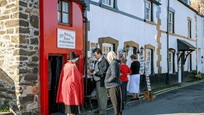 Visitors entering Conwy Castle being greeted by person in Welsh costume