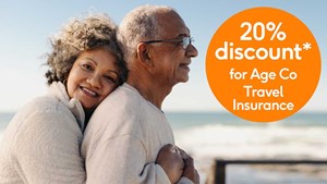 Older couple hugging on beach standing next to a 20% off roundel