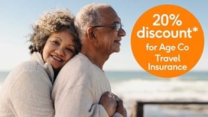 Older couple hugging on beach standing next to a 20% off roundel