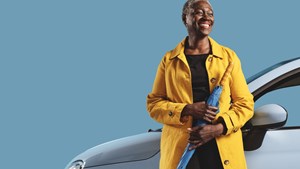 Black lady leaning against car window holding an umbrella