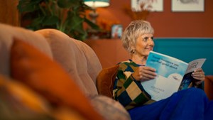 Lady sitting on the couch reading a travel insurance brochure