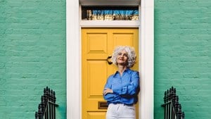 Older lady leaning on yellow front door