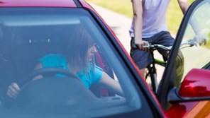 Woman opening car door as cyclist approaches from behind