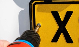 a uk number plate being removed with a screwdriver